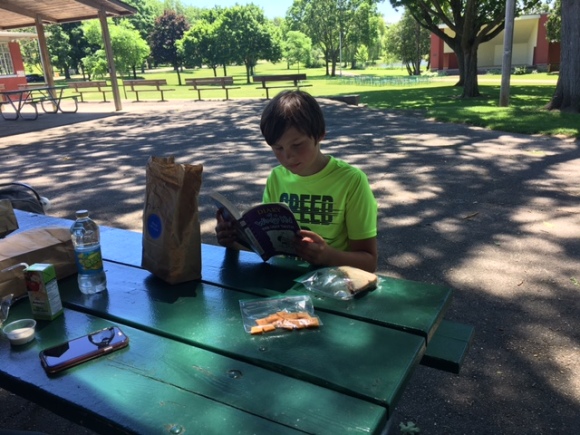 child sitting at picnic table reading book